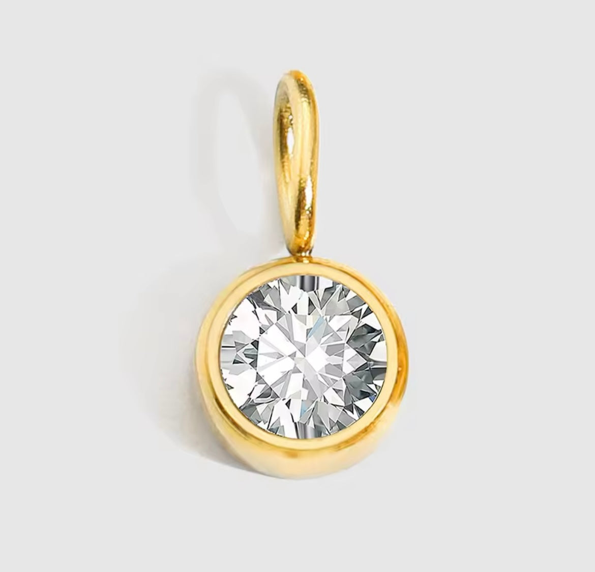 Gold-plated birthstone charm necklace with clear gem pendant.
