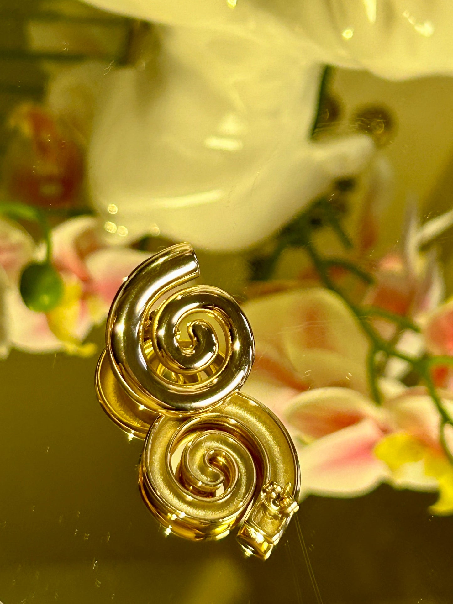 Geometric Spiral Stud Earrings with 18k gold plating on display.