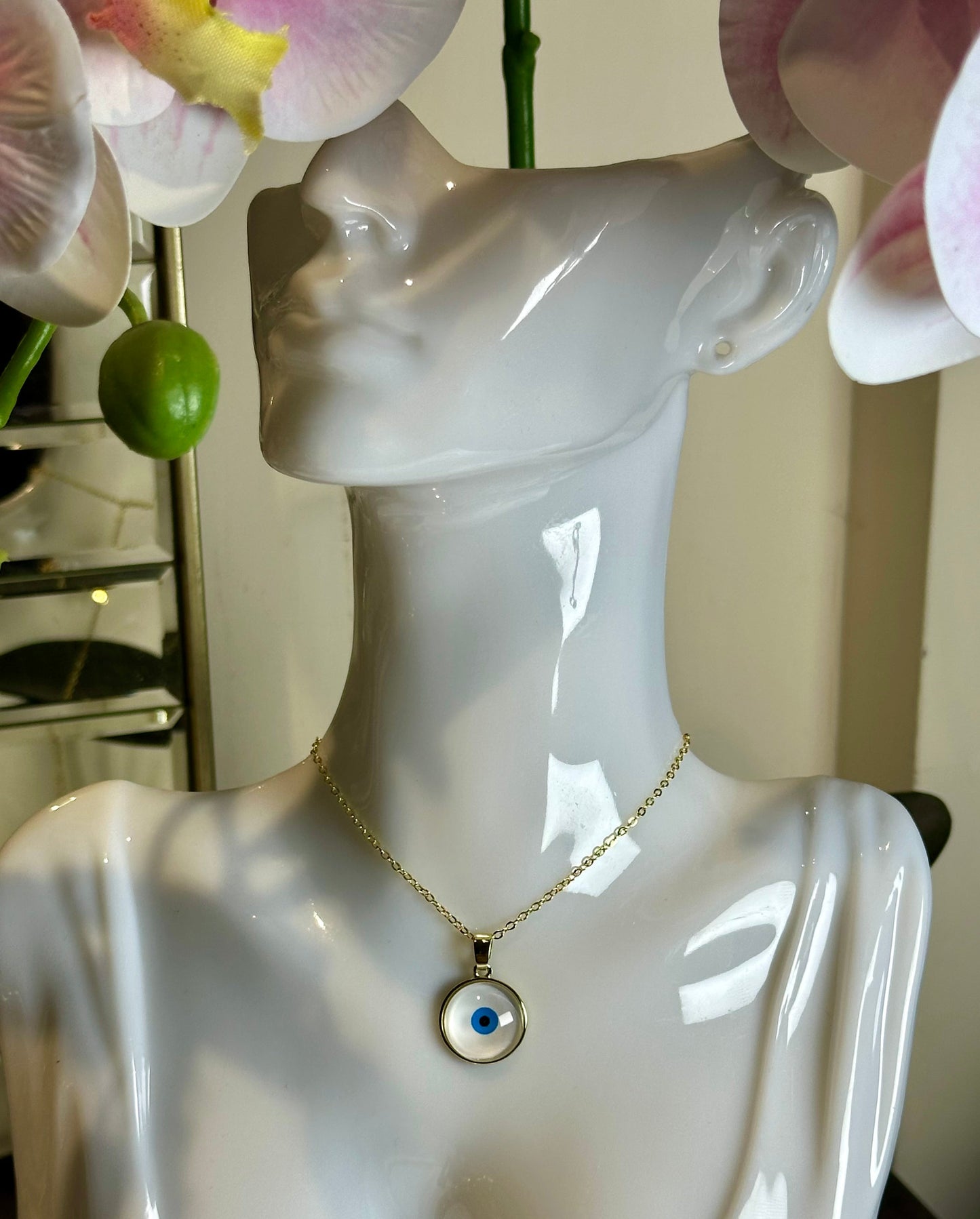 Round resin evil eyes necklace with gold-plated chain on mannequin.
