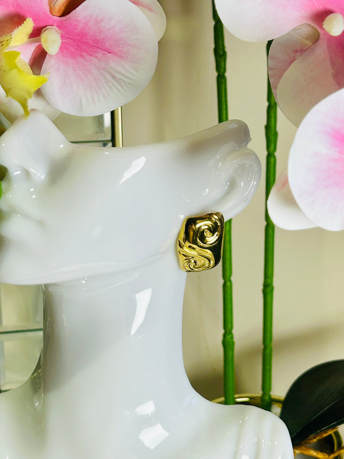 Square Embossed Spiral Earring with 18K gold plating displayed on a mannequin bust against floral backdrop.