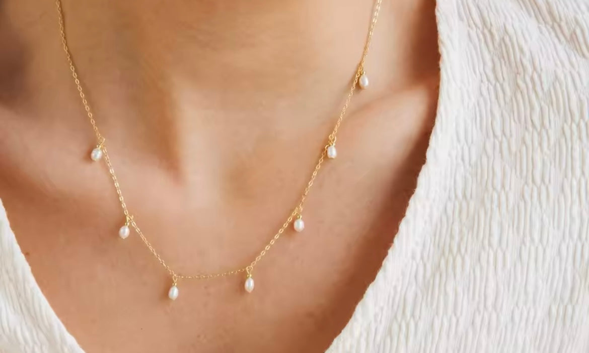 Gold-plated stainless steel teardrop imitation pearl necklace on neck.