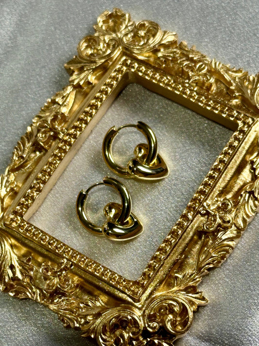 Heart Huggie Earrings displayed in an ornate golden frame.