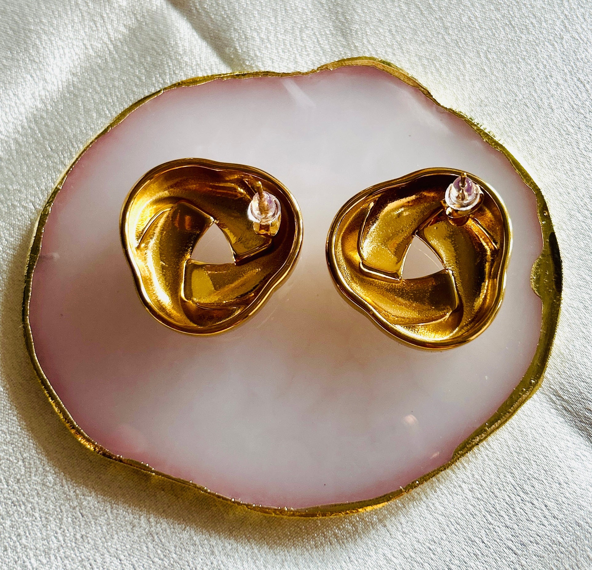 Vintage braided stud earring made of 18k gold plated stainless steel on a decorative dish.