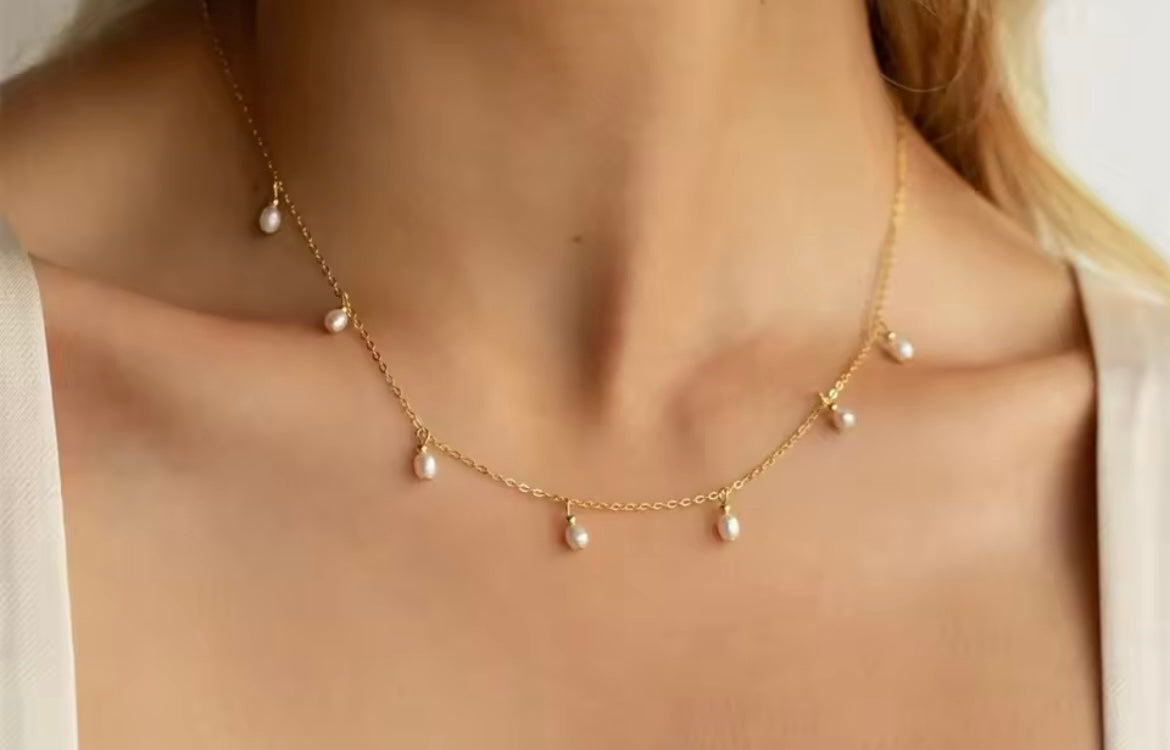 Gold-plated stainless steel teardrop imitation pearl necklace on model.